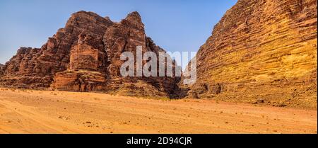 A landscape of rocky outcrops and red sand in the arid desert of Wadi Rum Stock Photo