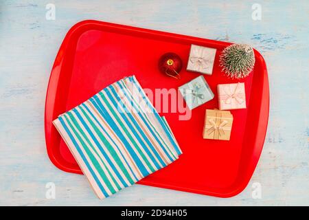 Christmas composition. Christmas gift boxes. Red plastic dining tray on the table. Stock Photo