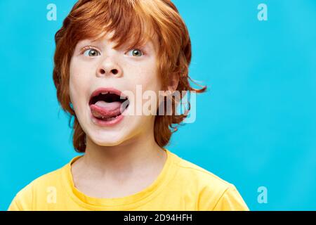 portrait of a red-haired boy sticking out tongue grimaces  Stock Photo