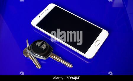 Smartphone and car keys on blue background Stock Photo