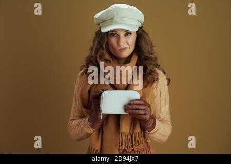 Hello autumn. unhappy stylish woman in scarf with wallet and leather gloves against bronze background. Stock Photo