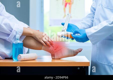 close-up hand wear medical gloves doctor in medical gloves holds artificial boneof the foot and examines a sore ankle in clinic, Concept of medical or Stock Photo