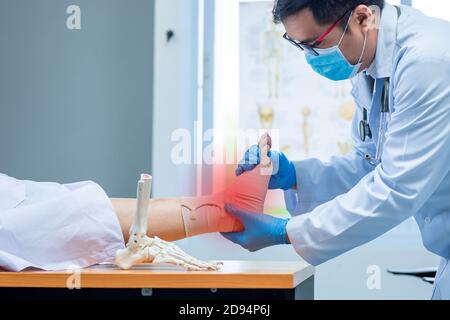 close-up hand wear medical gloves doctor in medical gloves holds artificial boneof the foot and examines a sore ankle in clinic, Concept of medical or Stock Photo