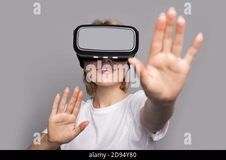 Blonde woman in white clothes is touching something while wear a vr headset