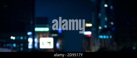 Blurred banner background of the city at night with bokeh light from buildings and ad signs Stock Photo