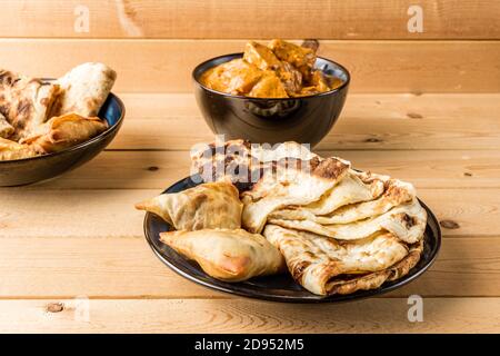 Indian snacks samosa garlic naan bread butter chicken on wooden table Stock Photo