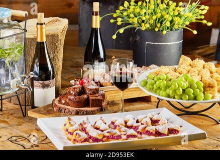 Sweet table with a selection of cakes and pastries with grapes and red wine. Stock Photo
