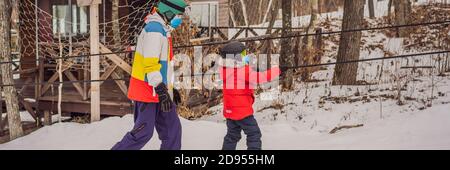 BANNER, LONG FORMAT Snowboard instructor teaches a boy to snowboarding wear medical masks due to the COVID-19 coronavirus. Activities for children in Stock Photo