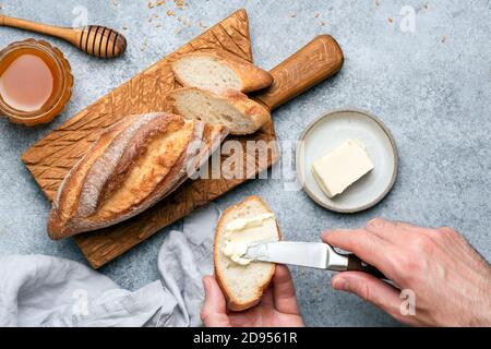 Spread butter on baguette bread. Bread and butter toast Stock Photo