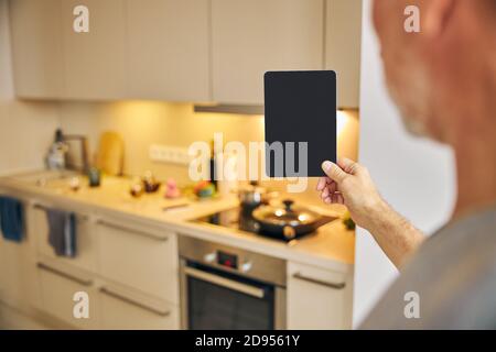 Gentleman holding a tablet in his cozy kitchen Stock Photo