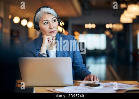 Beautiful woman in headphones sitting at the table with laptop Stock Photo