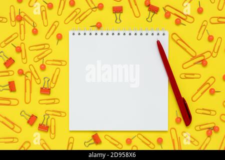 Notepad and red pen on a yellow paper background. Open notebook and supplies on the table. Template with copy space, flat design, layout. Planning con Stock Photo