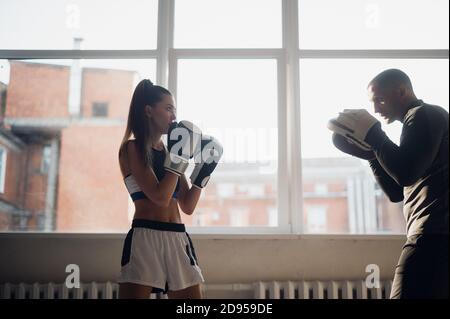 A man and a woman sparring partners train in the fighters training hall in boxing gloves with paws Stock Photo