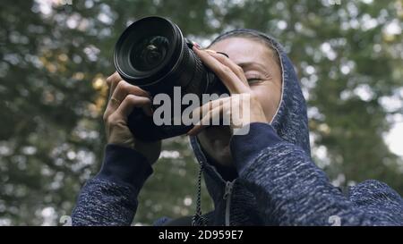 Traveler photographing scenic view in forest. One caucasian woman shooting close up look. Girl take photo video on dslr mirrorless camera. Stock Photo