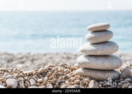 Zen relax background. A pyramid of stones on the beach in clear sunny weather. Background for meditation, yoga and massage Stock Photo