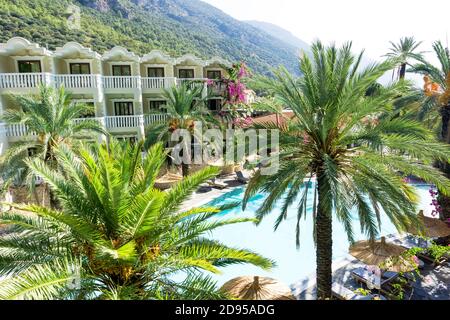 Luxury tropical resort or private villa with turquoise pool, sunbeds, umbrellas and palms. Relaxation and vacation concept. Stock Photo