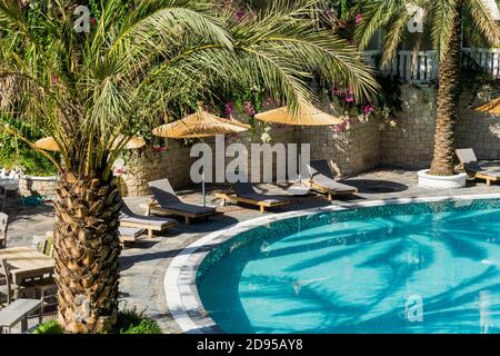 Luxury tropical resort or private villa with turquoise pool, sunbeds, umbrellas and palms. Relaxation and vacation concept. Stock Photo
