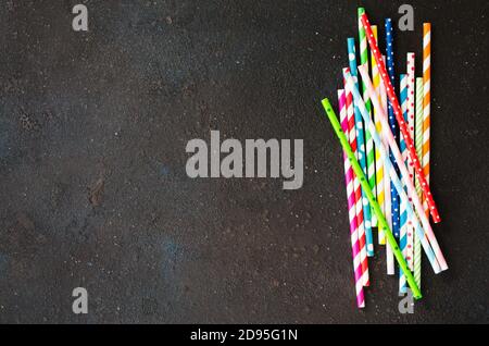 Colorful paper straws of different colors for cocktails and drinks on dark background. Stock Photo