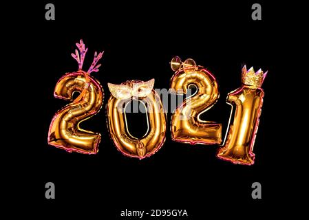 Gold numbers 2021 on black background in carnival accessories, new year party Stock Photo
