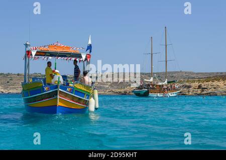 MARSAXLOKK, MALTA - Jan 30, 2019: Traditional colourful fishing boat sailing in crystal blue waters, near Marsaxlokk village in Malta. Stock Photo