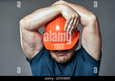 Extremely stressed engineer in hardhat against gray background Stock Photo