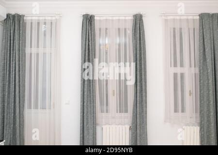 High windows and curtains in a bright living room Stock Photo