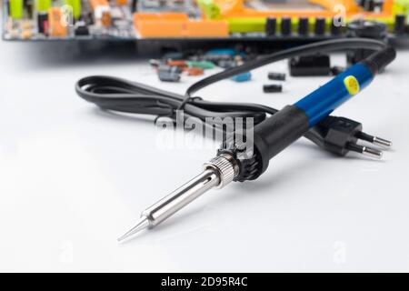 soldering iron on the background of a computer Board and capacitors in soft focus. The concept of repair and service Stock Photo