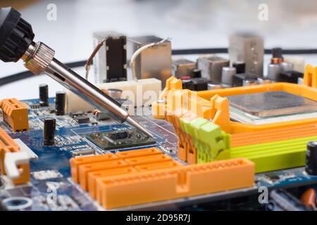 use a soldering iron to solder the electronic part to the Board. Computer repair. Macrophotography. Stock Photo