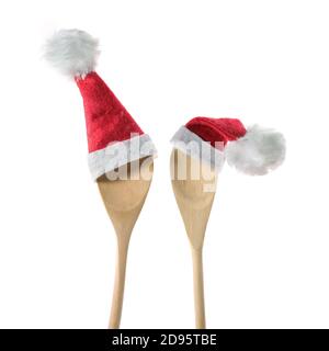 Two wooden cooking spoons with red Santa Claus hats isolated on a white background, Christmas dinner invitation concept, copy space, selected focus Stock Photo