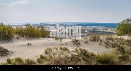 Panoramic view of the sand dunes with vegetation, in the background blue sea and sky with clouds, Kursh Spit, Russia Stock Photo