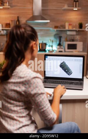 Back view of engineer working on turbine project in home office during night time. Industrial female engineer working on personal computer showing cad software. Stock Photo