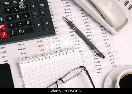 Financial analysts desktop with a calculator, coffee Cup, pen, Notepad, and documents Stock Photo