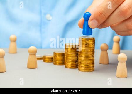 Career growth, salary increase. Man puts leader on stack of gold coins Stock Photo