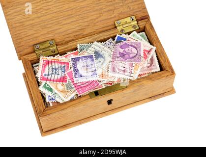 Small wooden box filled with old franked postage stamps isolated on a white background Stock Photo