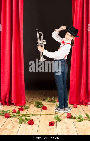 little girl playing trumpet on a gray background Stock Photo