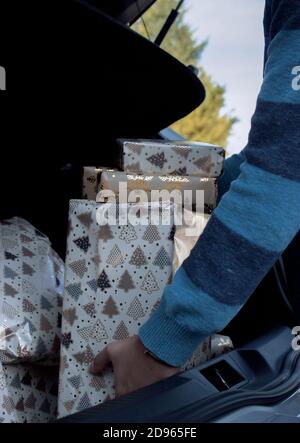 Man holds Christmas gifts that he has just bought to put under the Christmas tree at home. Christmas photograhy 2020. Christmas consumer. Stock Photo
