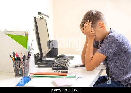 Kid with computer doing homework at home. Learning difficulties, online learning, education concept Stock Photo