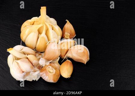 Smoked garlic bulbs on a slate stone background Stock Photo