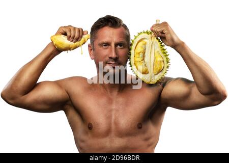 Male body-builder is holding fresh durian in hands next to his face. Isolated against white background. Stock Photo