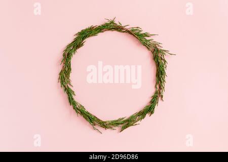Wreath made from conifer tree branches on a pink pastel background Stock Photo