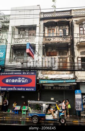 A tuk tuk in Bangkok, Thailand, is parked curbside waiting for a customer on a rainy afternoon. Stock Photo