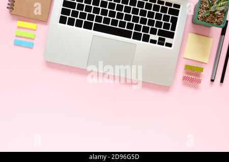 Home office desk with laptop, kraft notepad, sticky notes, succulent flower, pen, pencil, little clothespins on a pink pastel background Stock Photo