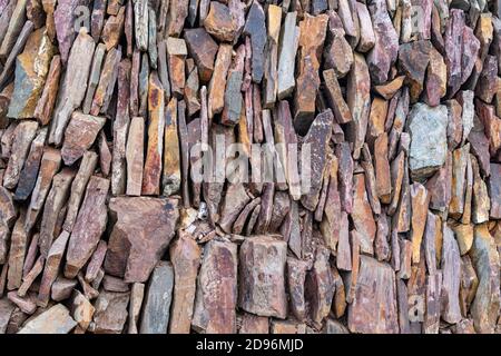 close up shot of a slate stone wall with varying colours of purple and grey Stock Photo