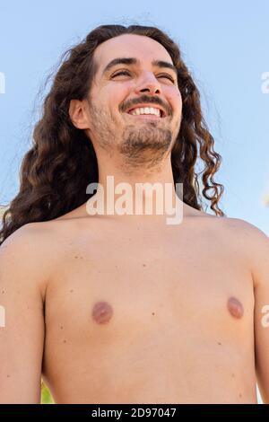 Vertical shot of an attractive young man with long curly hair Stock Photo