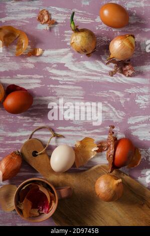 Eggs and onions on a rustic table, top down view. Easter eggs dyed in traditional natural dye - onion skins. Polish Easter tradition. Stock Photo