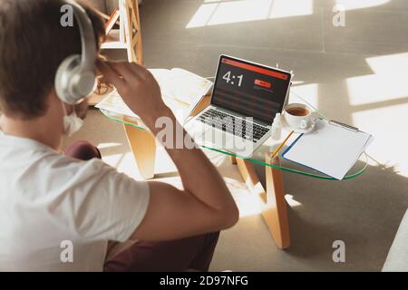 Man using laptop, screen with mobile app for betting. Device with match results on screen. Watching attented, listen to headphones. Gambling, betting, sport, finance, modern technologies concept. Stock Photo