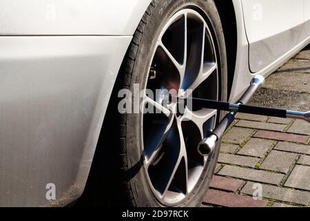 Changing car wheel or tire. Man using car jack to unscrew and change wheel. Summer or winter tire swap in the backyard. Stock Photo