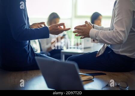 Business meeting of partners. Close up shot of human hands gesturing during discussion in foreground. Office workers works on blurred background.  Stock Photo