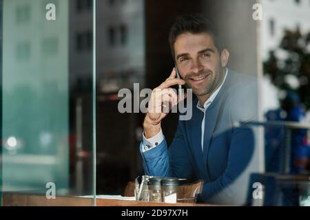 Young businessman talking on his cellphone inside of a cafe Stock Photo