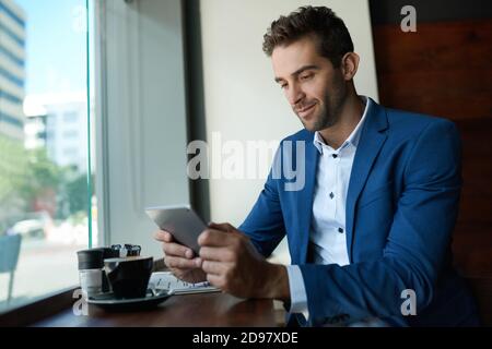 Young businessman using a tablet over coffee in a cafe Stock Photo
